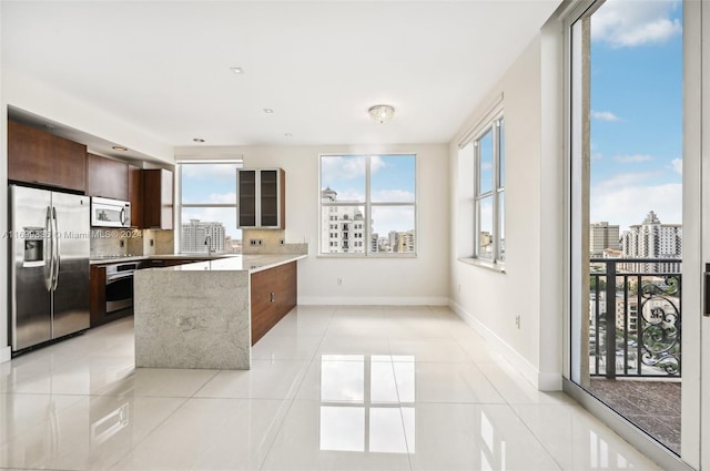 kitchen with light stone countertops, light tile patterned floors, stainless steel appliances, and decorative backsplash