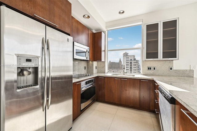 kitchen featuring decorative backsplash, appliances with stainless steel finishes, light stone countertops, and sink