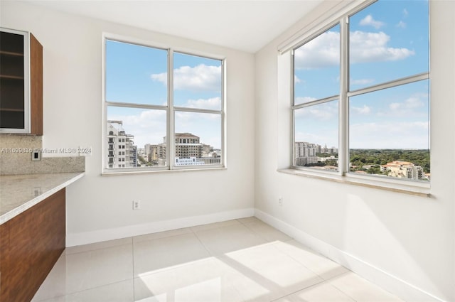 spare room with a wealth of natural light and light tile patterned flooring