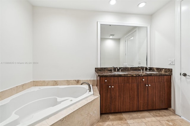 bathroom with tile patterned floors, vanity, and a relaxing tiled tub