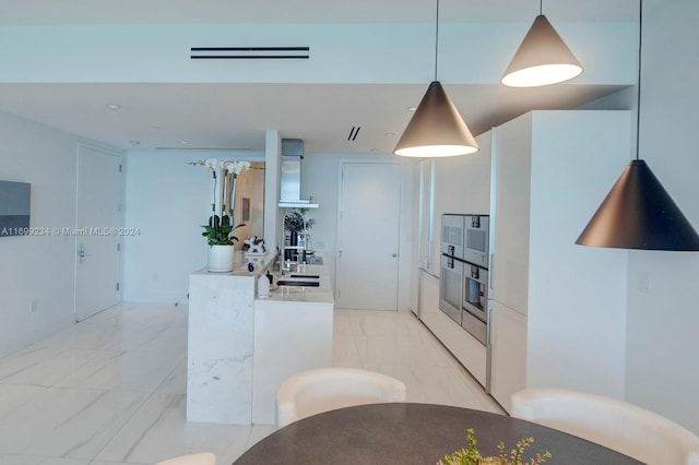 kitchen featuring sink, white cabinets, and hanging light fixtures