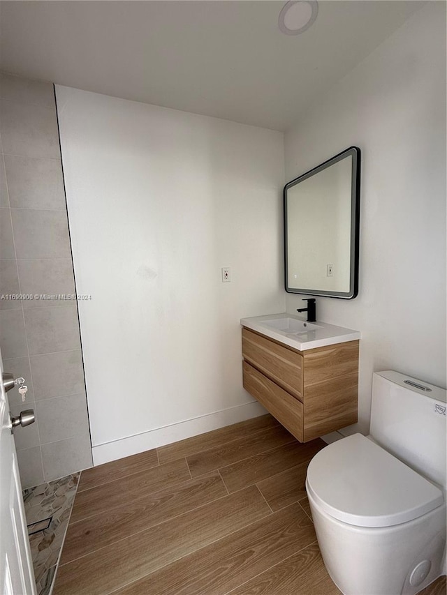 bathroom with toilet, vanity, and hardwood / wood-style flooring