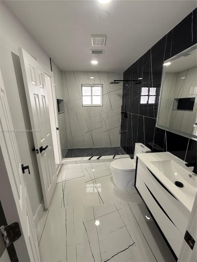 bathroom featuring tiled shower, toilet, tile walls, and vanity