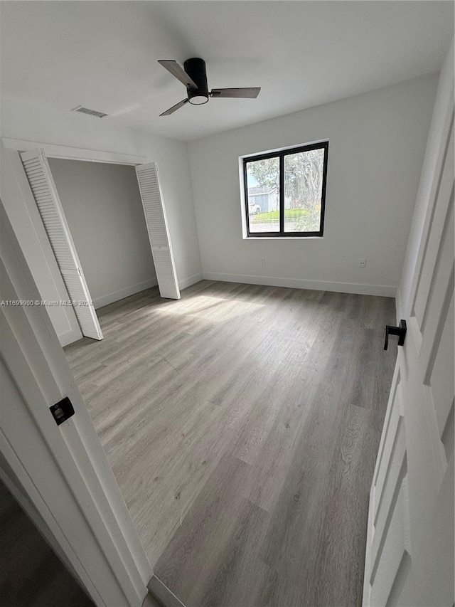 unfurnished bedroom with ceiling fan, a closet, and light hardwood / wood-style floors