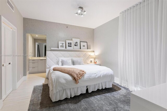 bedroom featuring ensuite bathroom and light hardwood / wood-style floors