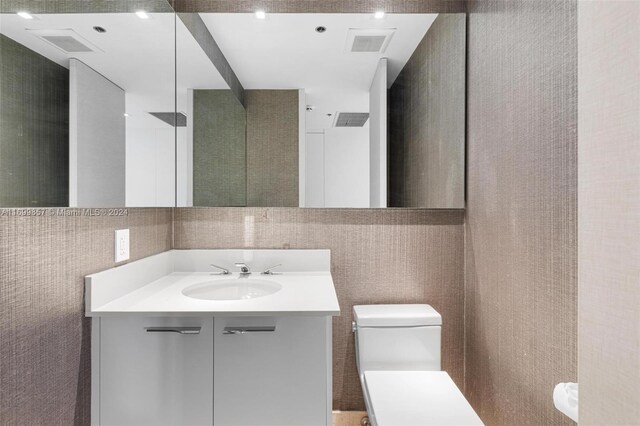 bathroom with vanity, tile walls, and toilet