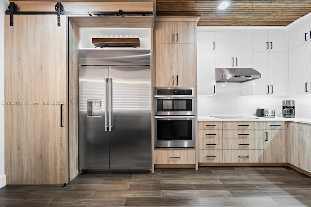 kitchen with white cabinets, a barn door, appliances with stainless steel finishes, dark hardwood / wood-style flooring, and wood ceiling