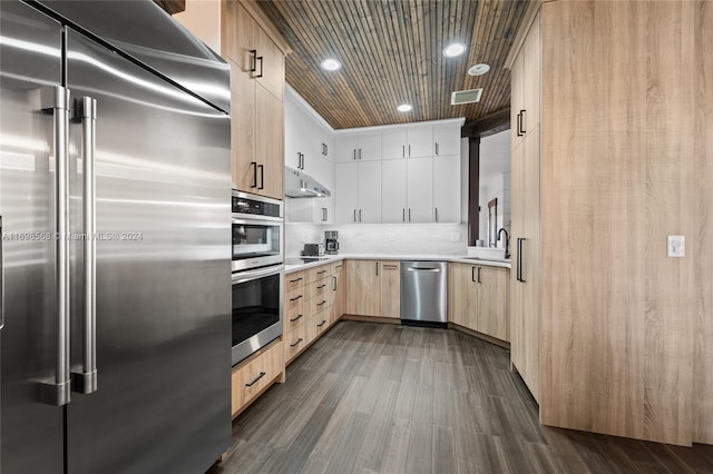 kitchen with dark wood-type flooring, stainless steel appliances, crown molding, light brown cabinetry, and white cabinets