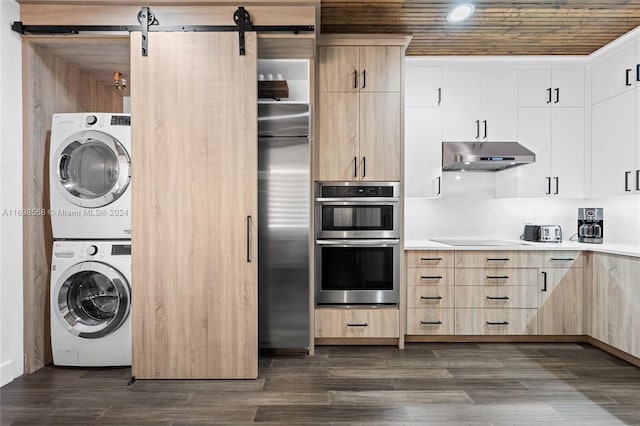 kitchen with light brown cabinets, white cabinets, stacked washer and dryer, a barn door, and stainless steel appliances