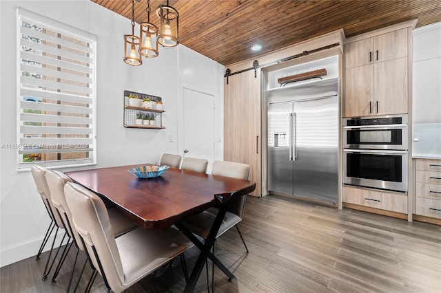 dining space featuring a barn door, light wood-type flooring, and wooden ceiling