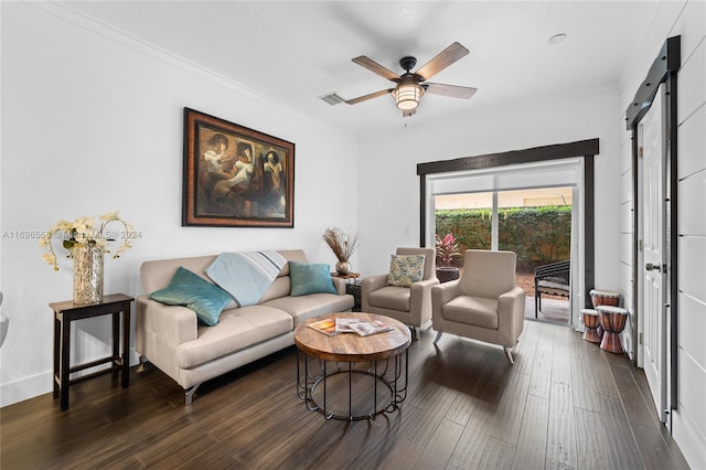 living room featuring a barn door, ceiling fan, dark wood-type flooring, and ornamental molding