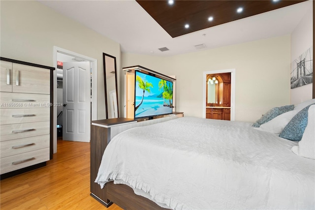 bedroom with light hardwood / wood-style floors and ensuite bath