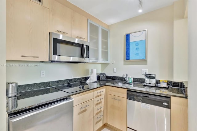 kitchen featuring light brown cabinetry, sink, appliances with stainless steel finishes, and dark stone counters