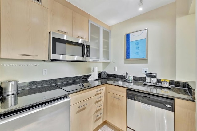 kitchen featuring appliances with stainless steel finishes, sink, light brown cabinetry, and dark stone countertops