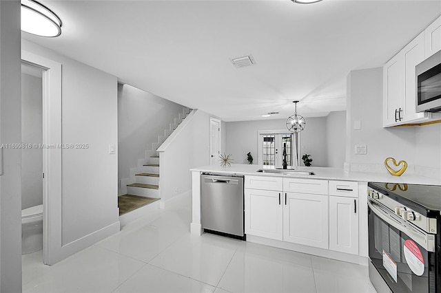 kitchen with sink, appliances with stainless steel finishes, hanging light fixtures, white cabinets, and kitchen peninsula