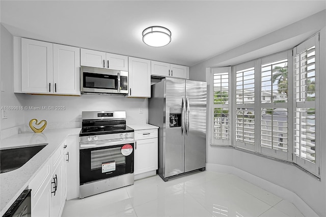 kitchen featuring stainless steel appliances, white cabinetry, sink, and light stone counters