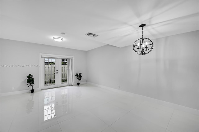 tiled spare room featuring french doors and a chandelier