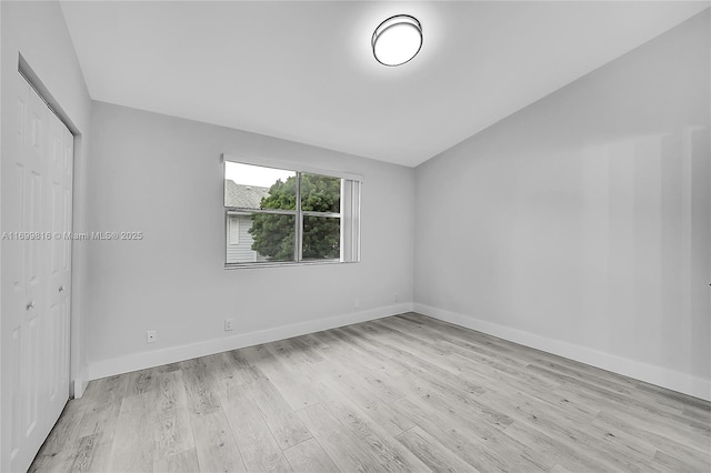 spare room with vaulted ceiling and light hardwood / wood-style floors