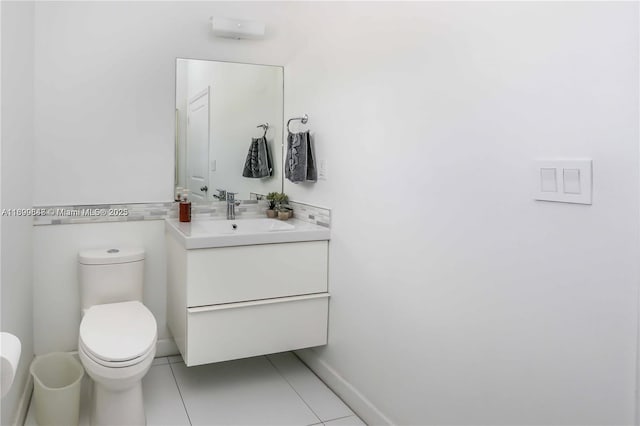 bathroom featuring toilet, tile patterned flooring, vanity, and baseboards