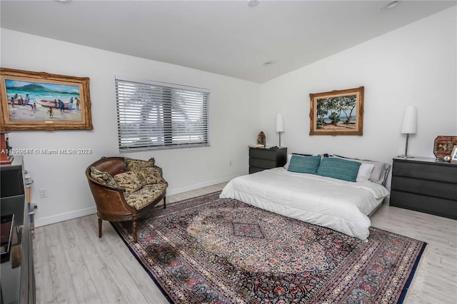 bedroom with light hardwood / wood-style floors and lofted ceiling