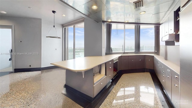 kitchen featuring kitchen peninsula, a kitchen breakfast bar, expansive windows, dark brown cabinets, and a water view