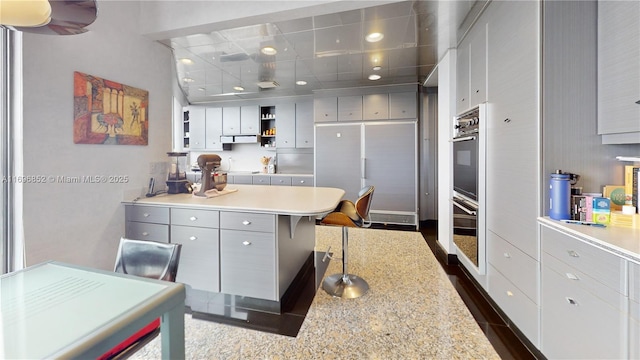 kitchen featuring a kitchen bar, gray cabinetry, and double oven