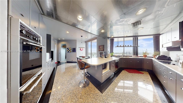 kitchen with sink, oven, a breakfast bar area, dishwashing machine, and black electric stovetop