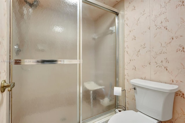 bathroom featuring toilet and an enclosed shower