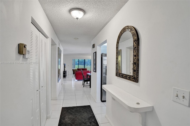 hall with light tile patterned floors and a textured ceiling