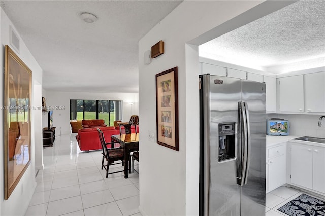 kitchen with white cabinetry, stainless steel fridge, and light tile patterned floors