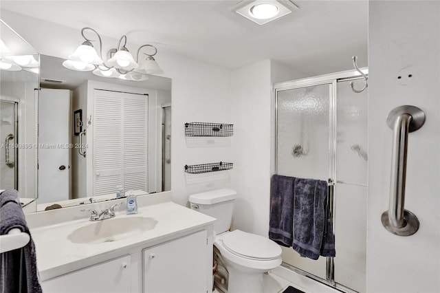 bathroom featuring vanity, a shower with shower door, and toilet