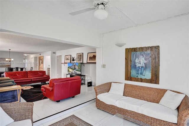 living room featuring ceiling fan with notable chandelier, light tile patterned floors, and a textured ceiling