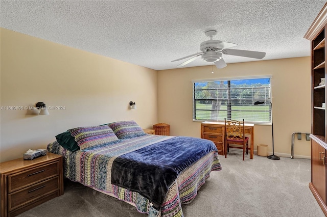 bedroom with ceiling fan, light colored carpet, and a textured ceiling