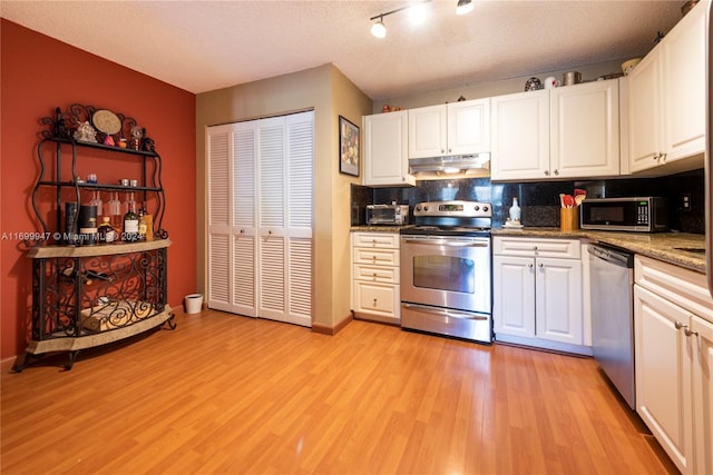 kitchen with decorative backsplash, a textured ceiling, stainless steel appliances, light hardwood / wood-style floors, and white cabinetry