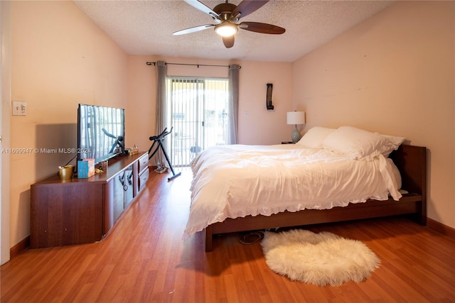 bedroom with ceiling fan, wood-type flooring, a textured ceiling, and access to outside