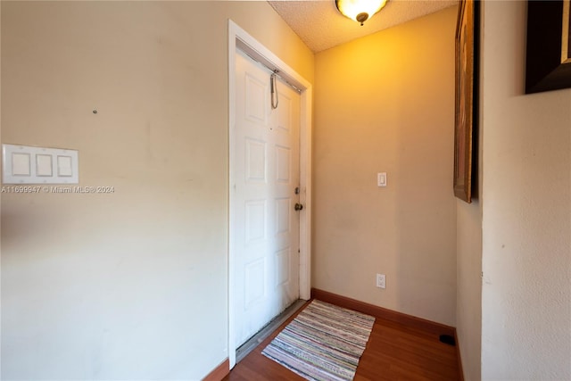 doorway to outside with dark wood-type flooring and a textured ceiling