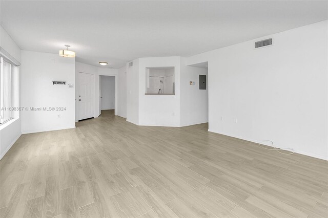 unfurnished room with electric panel and light hardwood / wood-style flooring