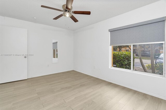 empty room featuring ceiling fan, a textured ceiling, and light wood-type flooring