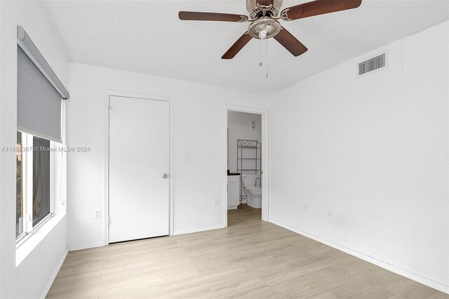 unfurnished bedroom with ensuite bath, ceiling fan, light hardwood / wood-style flooring, and a textured ceiling