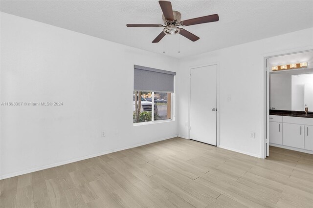 unfurnished bedroom featuring connected bathroom, ceiling fan, and light hardwood / wood-style flooring