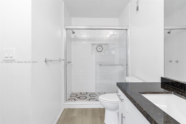 bathroom featuring walk in shower, hardwood / wood-style floors, vanity, and toilet