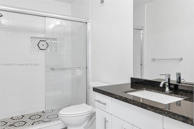 bathroom featuring vanity, toilet, and a shower with door