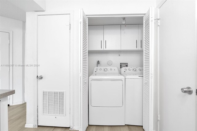 laundry room with cabinets, separate washer and dryer, and light hardwood / wood-style flooring