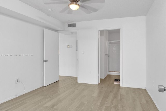 unfurnished bedroom with a walk in closet, ceiling fan, connected bathroom, light hardwood / wood-style floors, and a closet