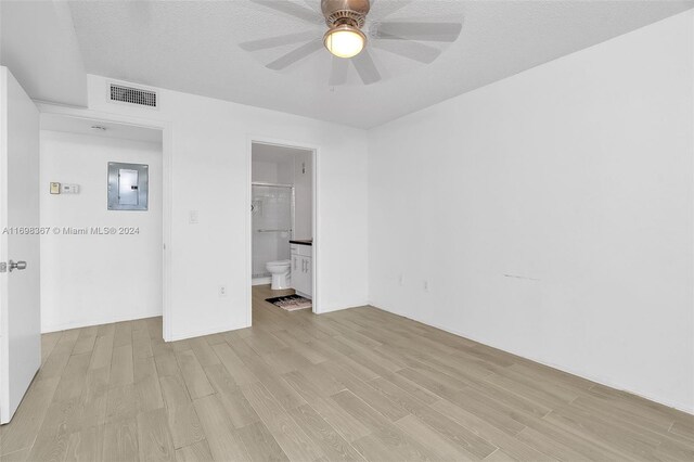 unfurnished bedroom with connected bathroom, ceiling fan, light hardwood / wood-style flooring, electric panel, and a textured ceiling