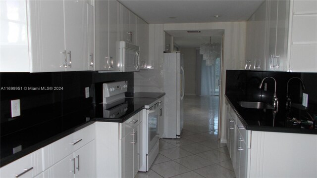 kitchen with decorative backsplash, white appliances, sink, light tile patterned floors, and white cabinetry