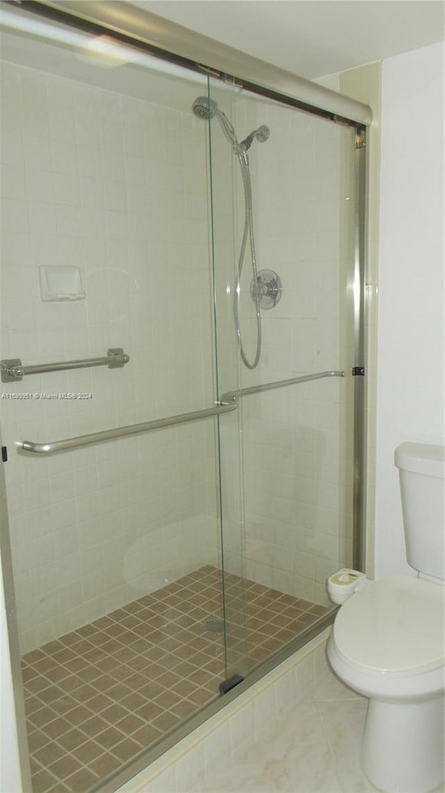 bathroom with toilet, tile patterned floors, and a shower with shower door