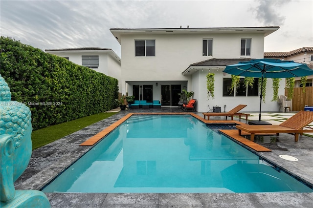 rear view of property featuring a fenced in pool and a patio area