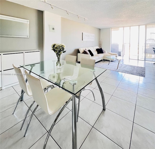 tiled dining space with a textured ceiling, rail lighting, and expansive windows