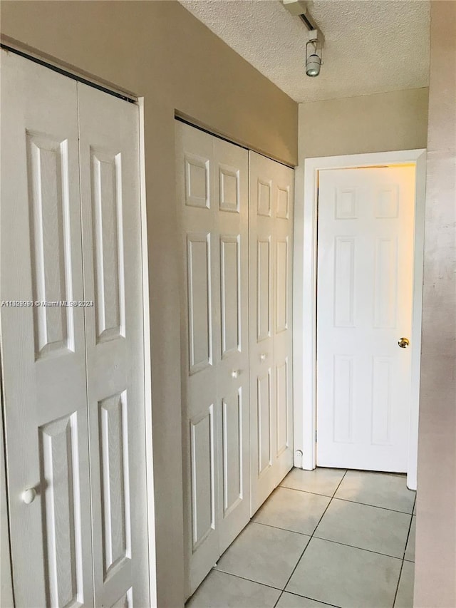 hallway featuring light tile patterned floors and a textured ceiling